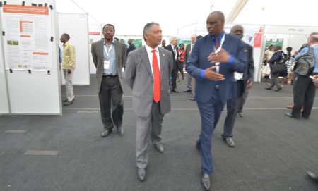 Picture of Minister Lubinda (middle) touring the poster stands while being briefed by Zambia Agriculture Research Institute (ZARI) Director Moses Mwale (right) as IITA Southern Africa Director Dr David Chikoye (left) walks alongside.