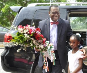 Picture of a smiling AfDB President being welcomed with flowers by Glory Paul, the daughter of an IITA staff member.