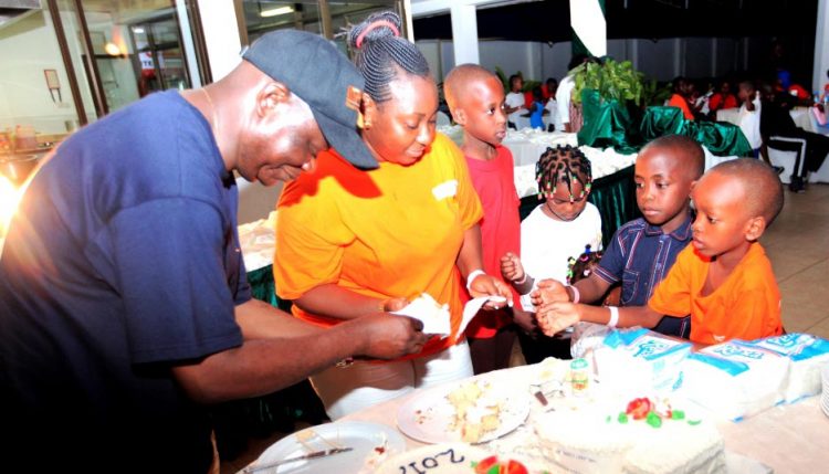 Picture of Manyong giving children of staff pieces of the 50th Anniversary cake.