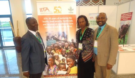 Picture of Denis Sonwa of CIFOR (Left), and Kantengwa Speciose IITA Rwanda (center), with a visitor at the IITA exhibition booth during the event at Kigali.