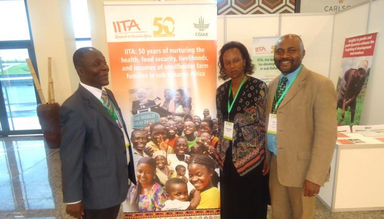 Picture of Denis Sonwa of CIFOR (Left), and Kantengwa Speciose IITA Rwanda (center), with a visitor at the IITA exhibition booth during the event at Kigali.