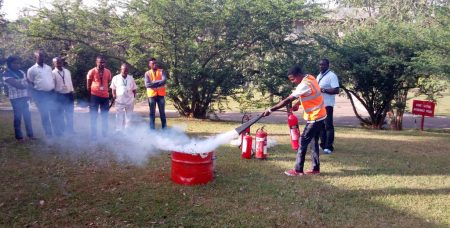 Picture of Security Superintendent James Adedayo guiding staff through practical firefighting techniques.