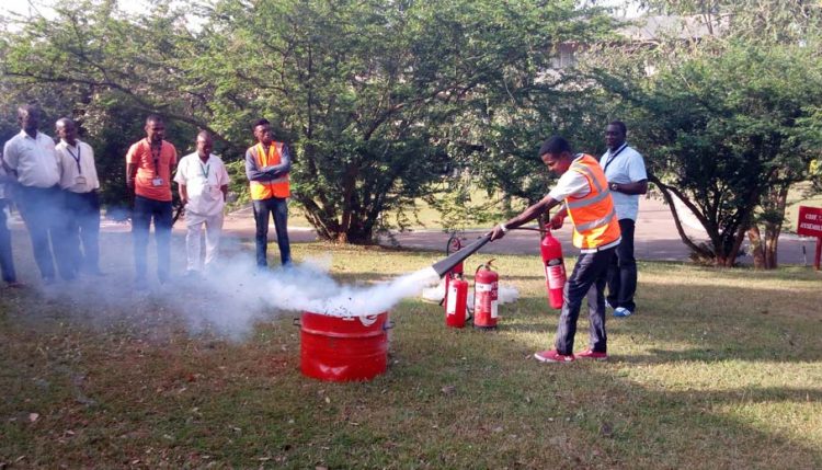 Picture of Security Superintendent James Adedayo guiding staff through practical firefighting techniques.