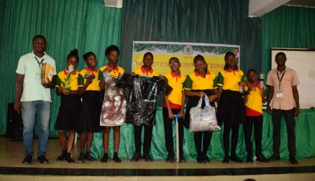 Picture of students, with Forest Center team members, displaying items made from plastic waste. Photo O.Olubodun
