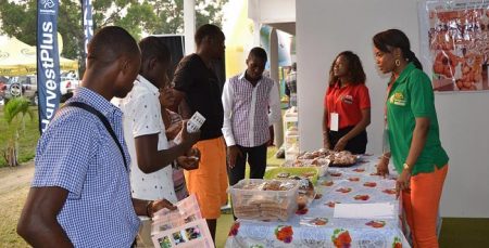 Picture of Agripreneurs Sandrine (in green) and Lisette (in red) briefing the visitors to the IYAKIN exhibition stand.