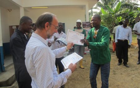 Picture of A farmer receiving a certificate during the graduation after a series of farmers field school training by PROSICA in Cameroon.